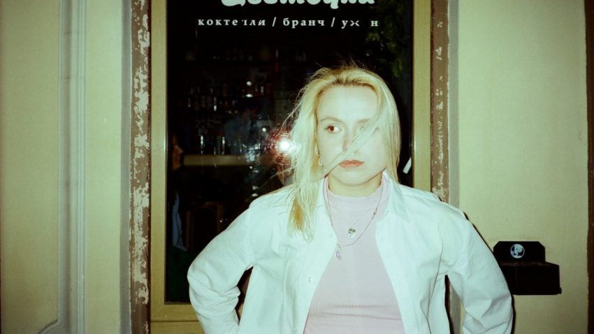 A woman stands in front of a window